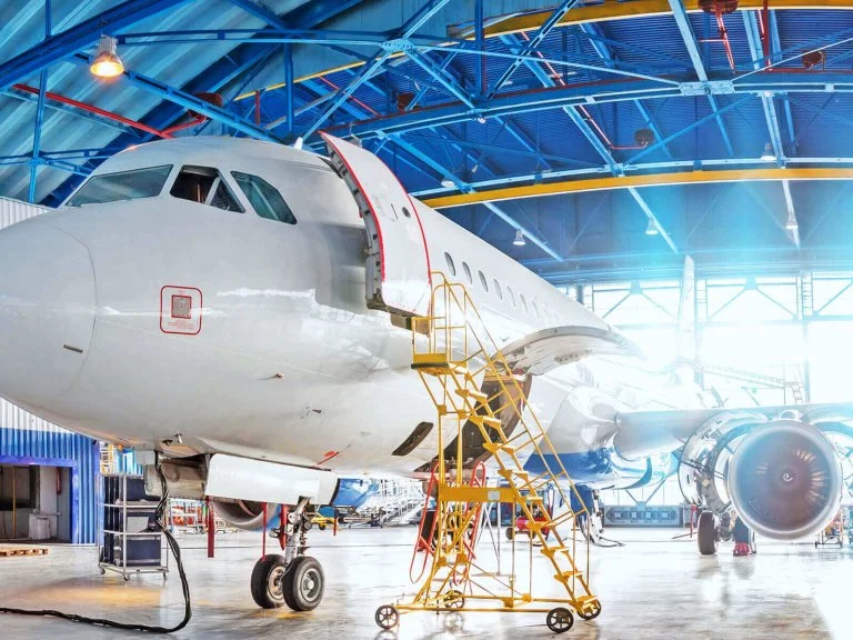 Aeronave en hangar de mantenimiento con estructura y plataformas de servicio