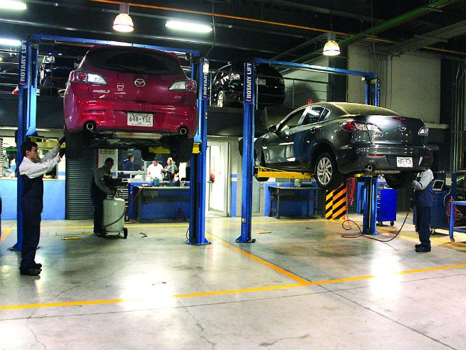 Técnicos de servicio trabajando sobre vehículos en elevadores